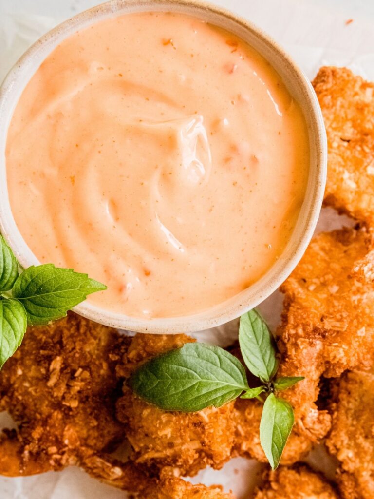 A bowl of bang bang sauce with coconut shrimp. 
