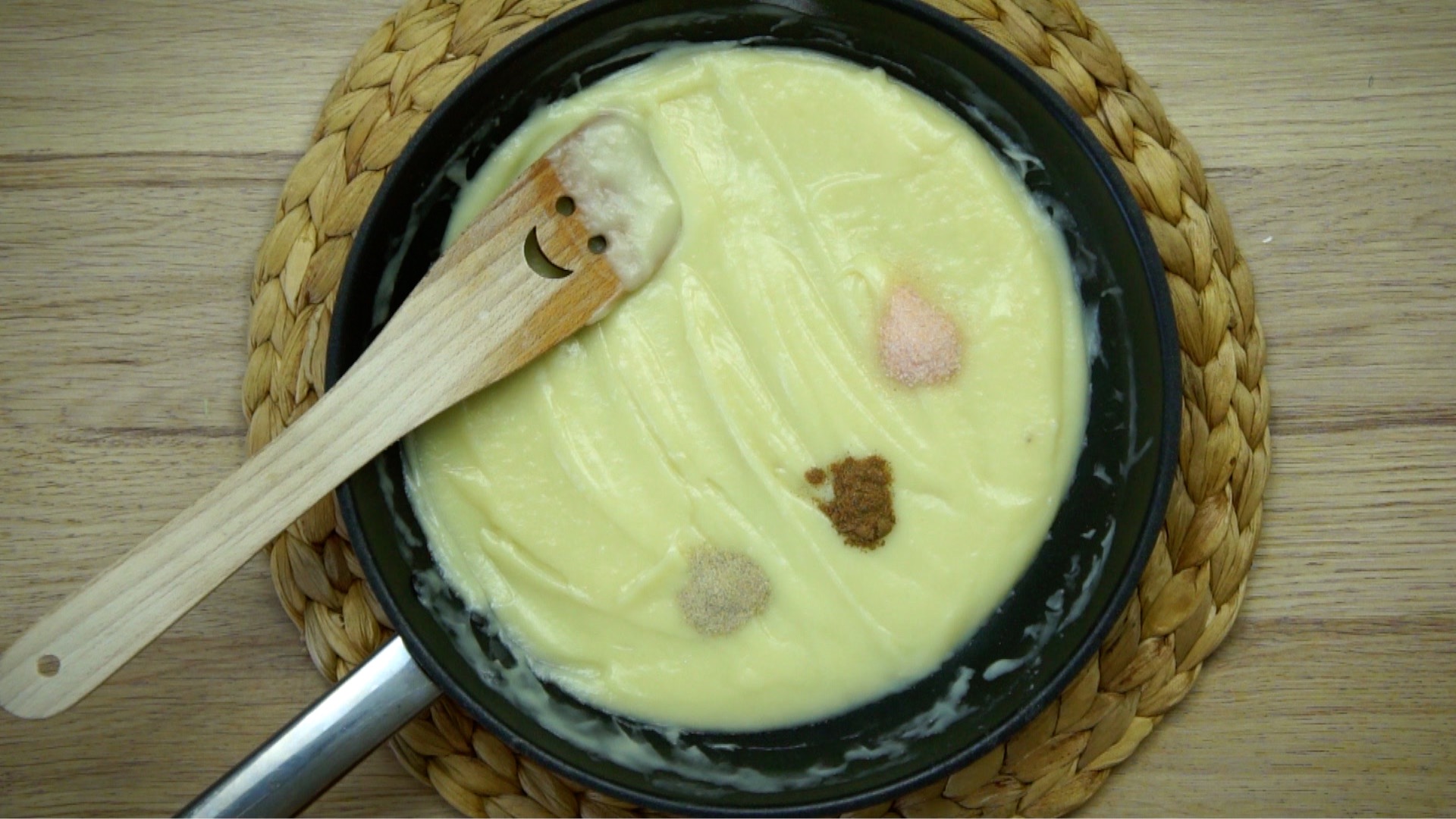 Frying pan with a light brown yellow sauce and three small heaps of seasoning.