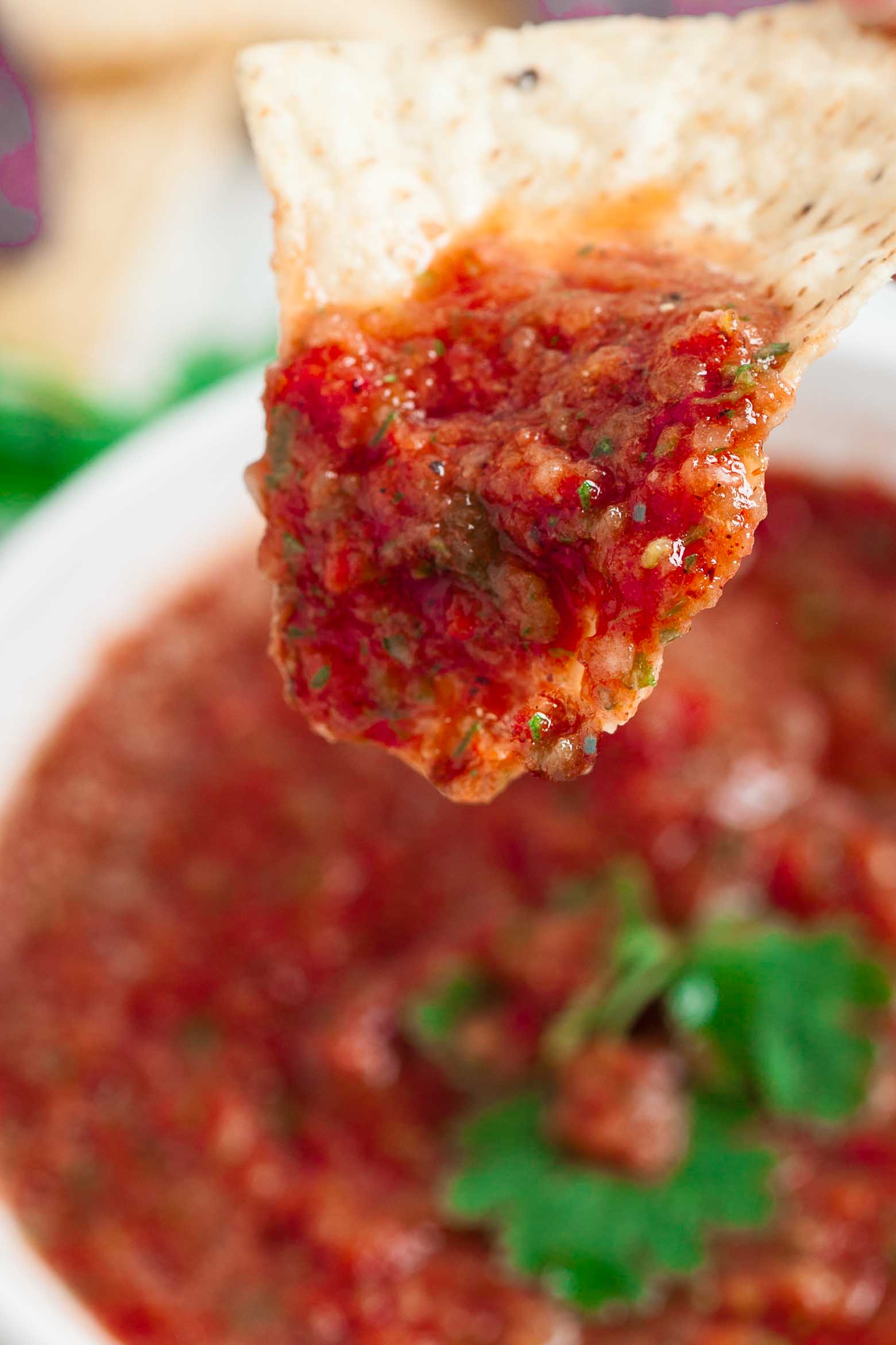 Closeup shot of a a person is dipping a tortilla into a bowl of salsa. 