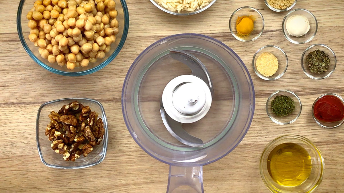 The ingredients of chickpea meatballs are measured in small glass containers 8 for seasoning and 3 for main ingredients. A food processor is empty in the middle.