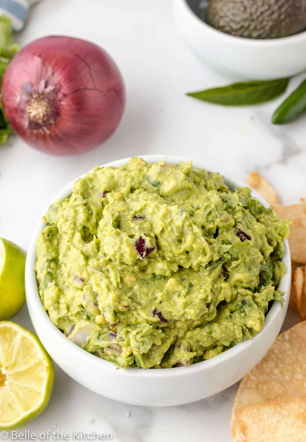 Copycat Chipotle Guacamole Recipe in a white bowl with limes and tortilla chips, made easy with just six ingredients.