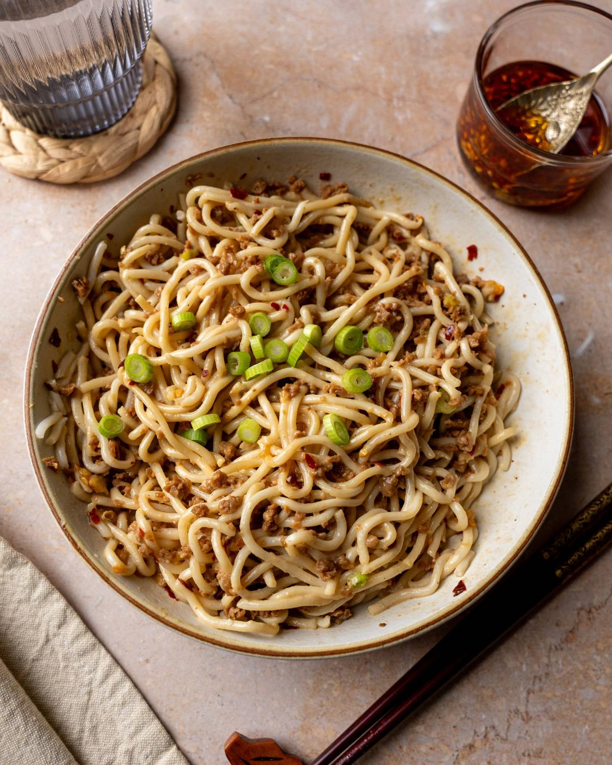 Vegan dan dan noodles in a large bowl served with chili oil on the side. 