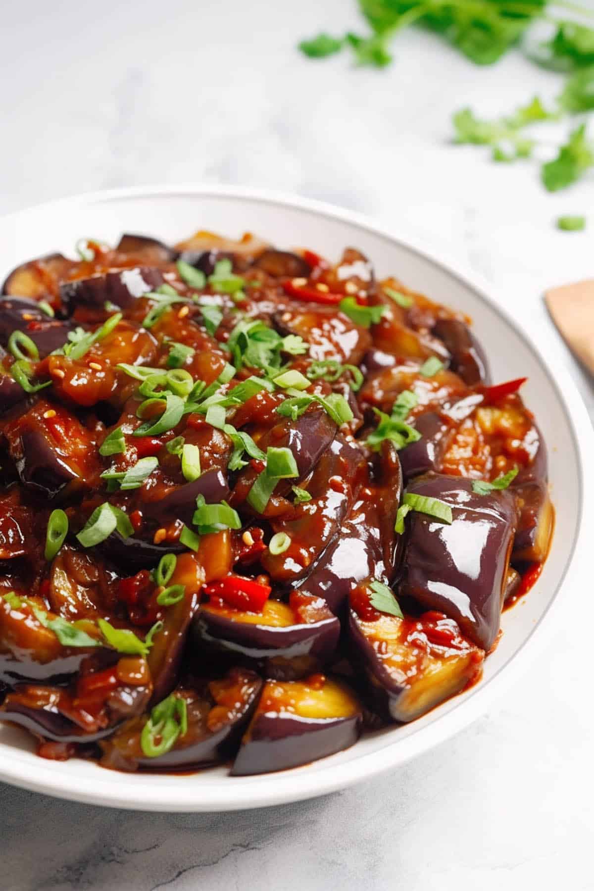 Chinese eggplant in garlic sauce in a white bowl. 
