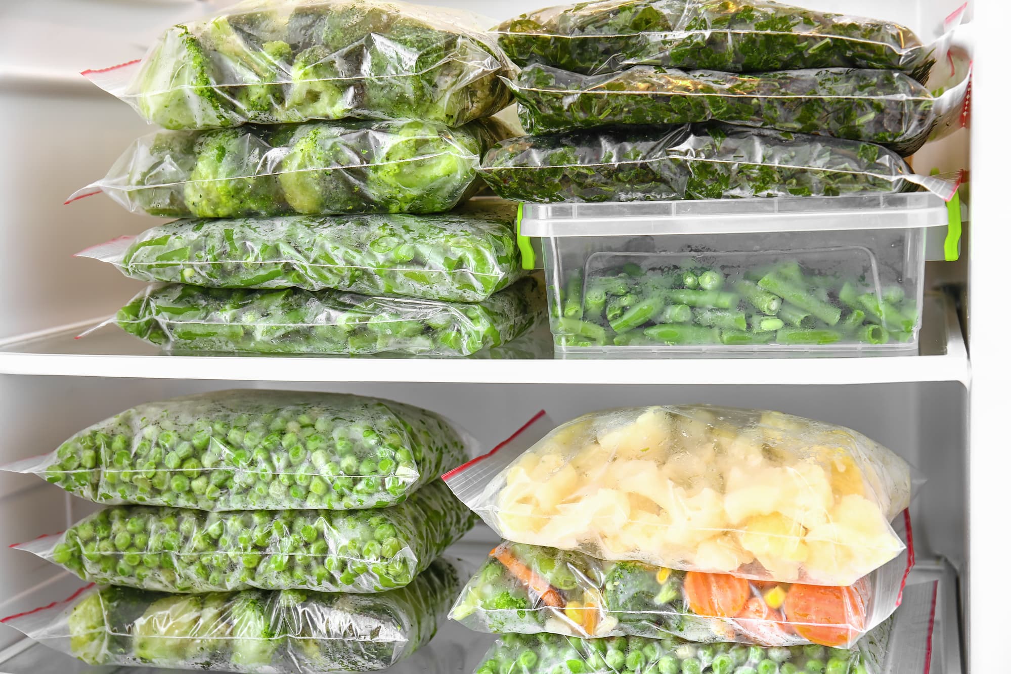 Different vegetables in ziplock bags stacked inside the freezer.