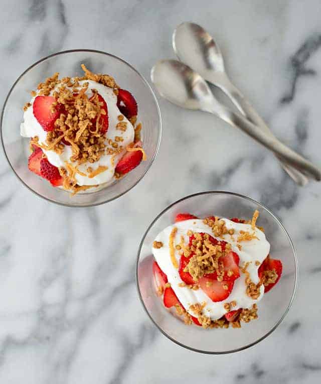 Two dessert glasses with vegan coconut cream berry parfaits.