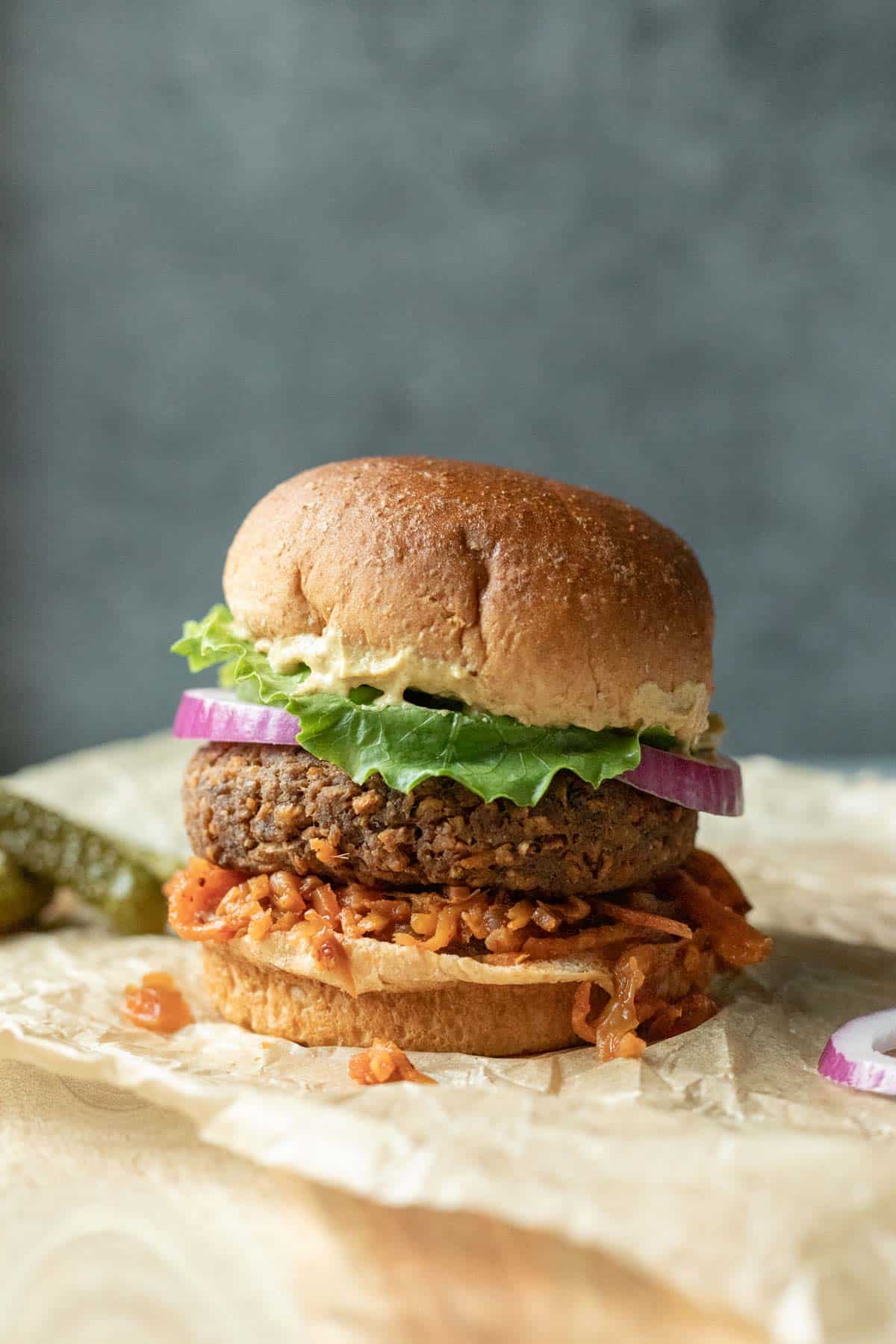 A loaded veggie burger on a bun against a blue background. 