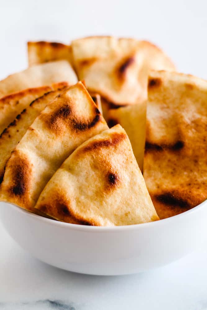 Homemade pita chips in a white bowl.