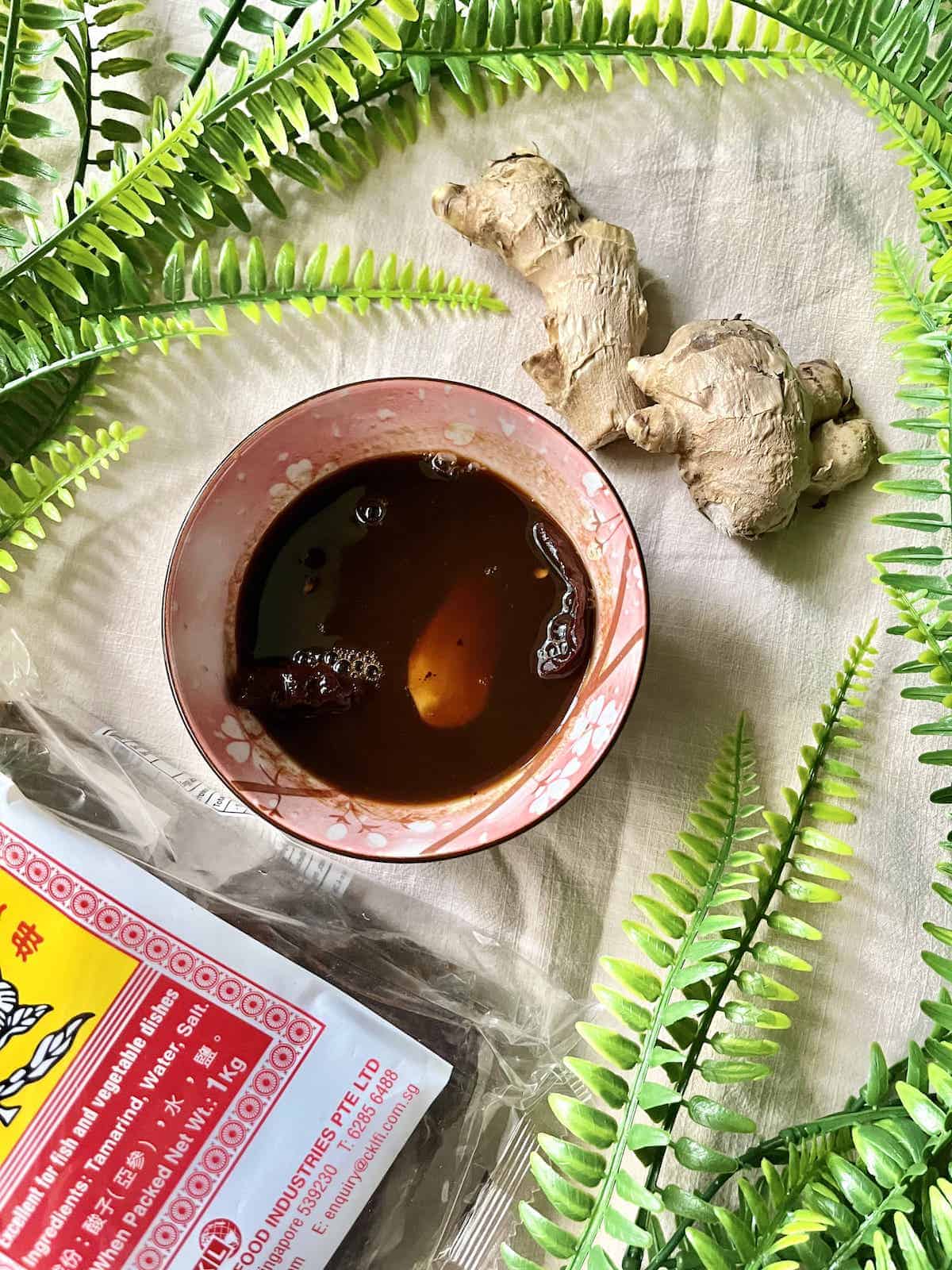 A bowl of homemade tamarind sauce with ginger next to it. 
