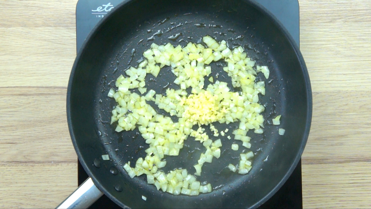 Black frying pan with minced onion and a small heap of garlic
