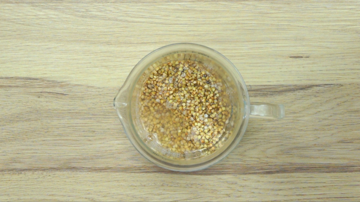 Buckwheat groats are soaked in water in a glass jar. 