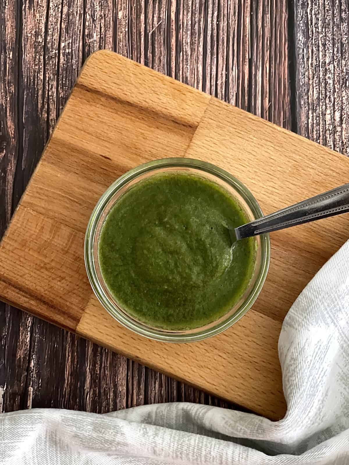 fresh mint chutney served in bowl with spoon on wooden board. 
