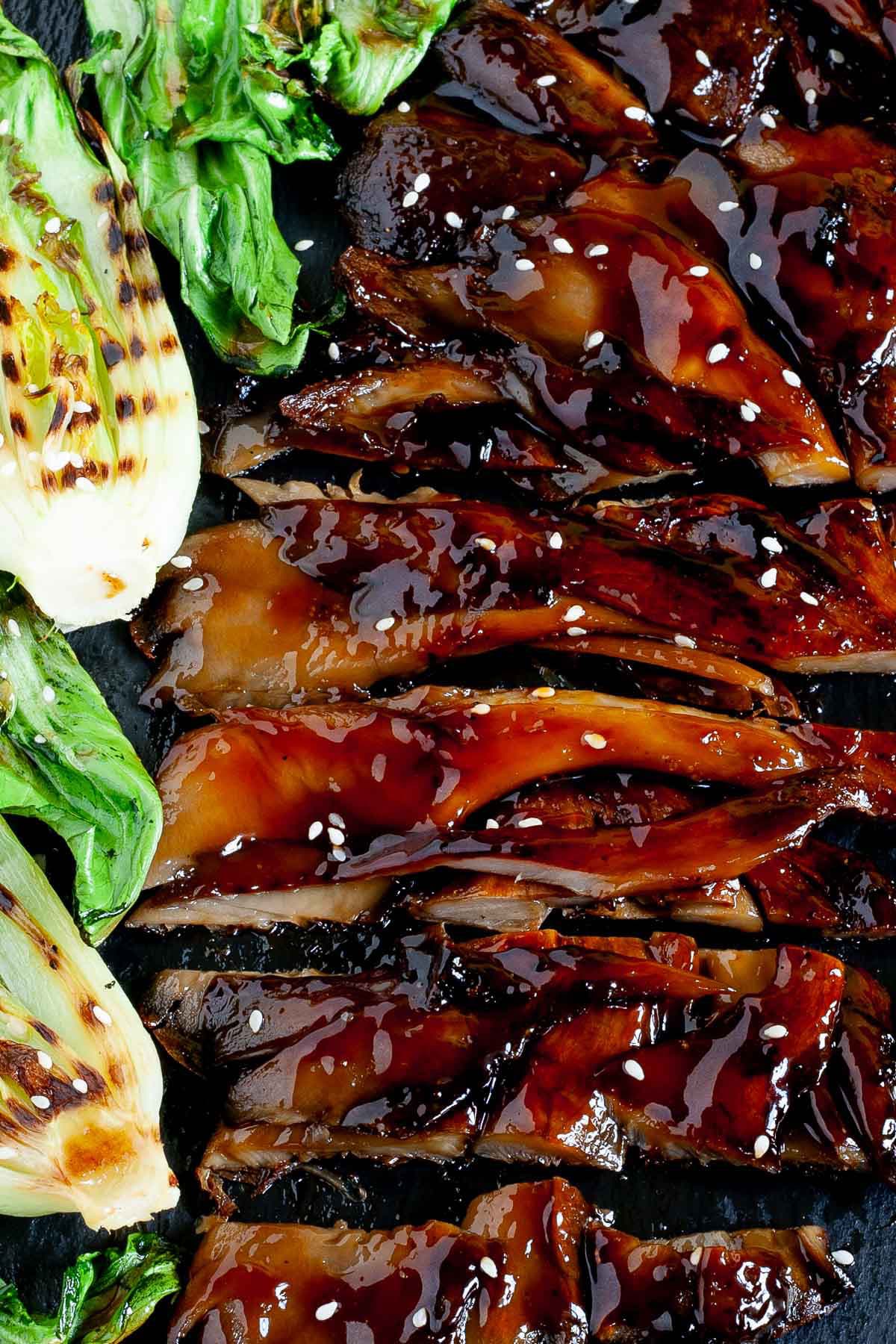 Black boardabove with crispy brown juicy flattened oyster mushroom clusters and half bok choy with charcoal stripes