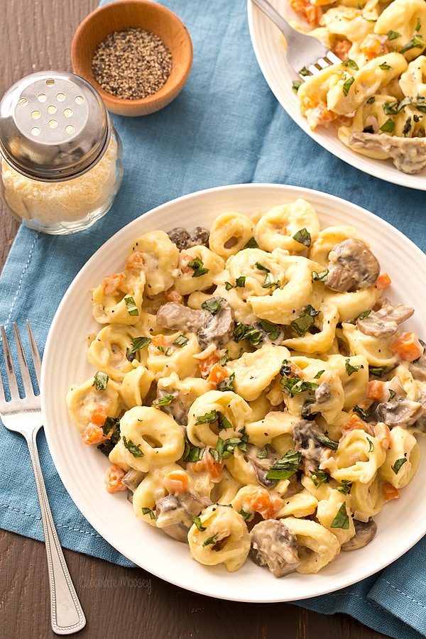 Portobello Mushroom Cheese Tortellini with alfredo sauce in a plate with a fork on the side.
