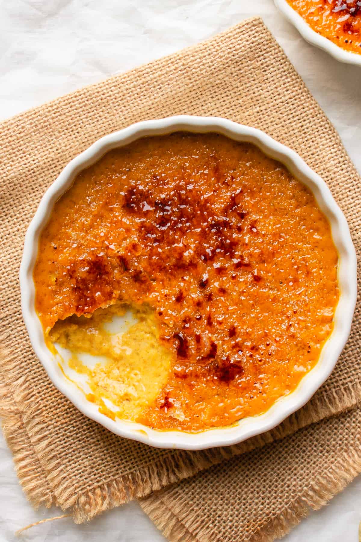 Pumpkin creme brûlée in a white ramekin on a burlap napkin. 