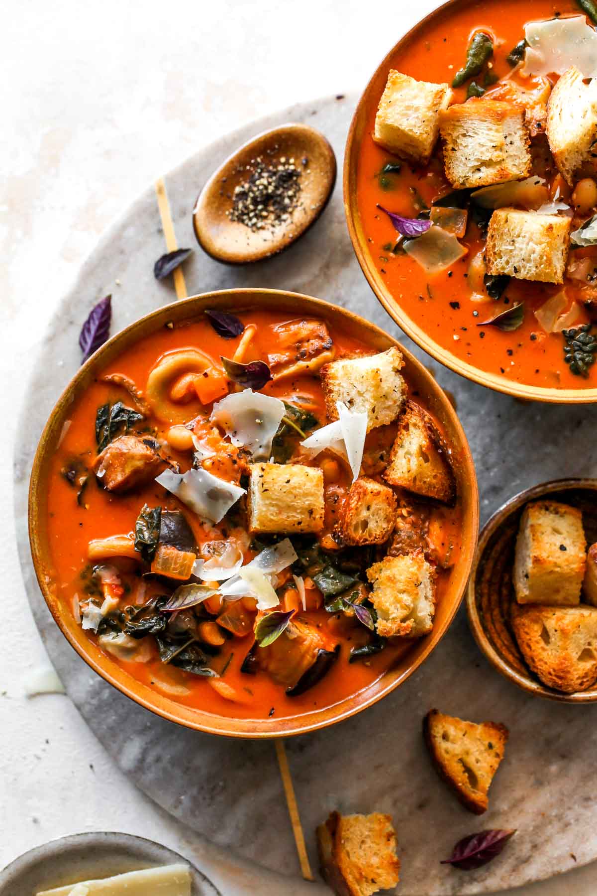 Roasted eggplant and tomato soup in a gold bowl topped with croutons.

