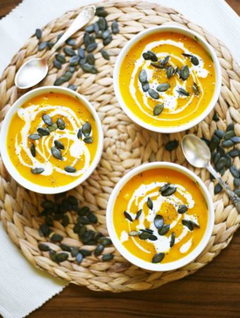 Simple Pumpkin Cream Soup from fresh Hokkaido pumpkin - 3 small bowl of pumpkin soup sprinkled with pumpkin seeds, chia seeds and dairy-free cream poured on top.