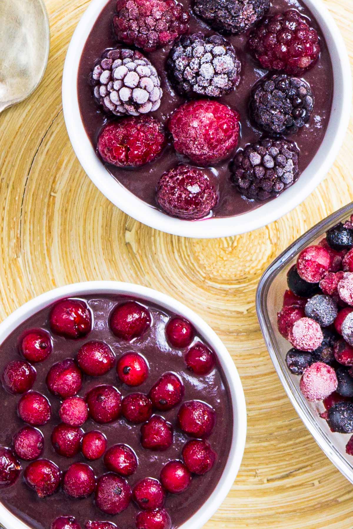 3 small bowls, one with vegan chocolate pudding topped with mixed berries, the other topped with red currant and one bowl is only fruits.