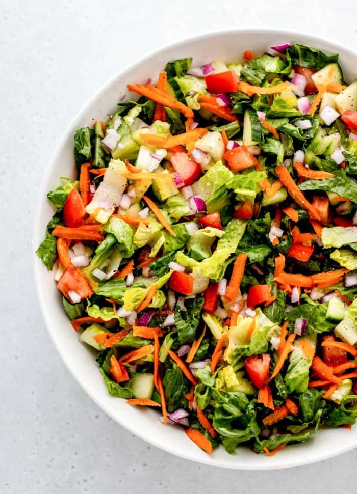 Overhead shot of tossed green salad in a white bowl. 