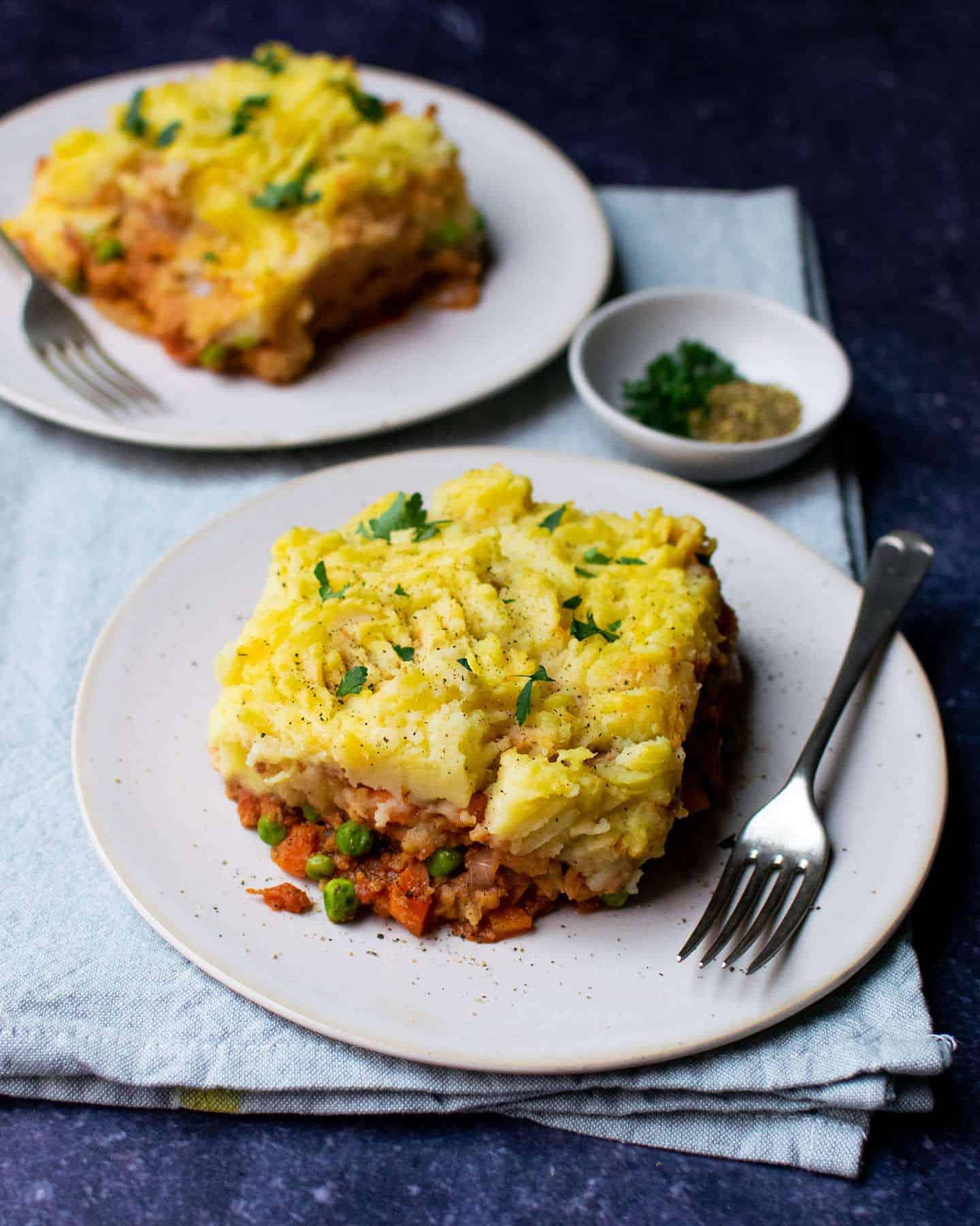 TVP Shepherd's pie on a white plate with a fork next to it, laying on a blue cloth. 