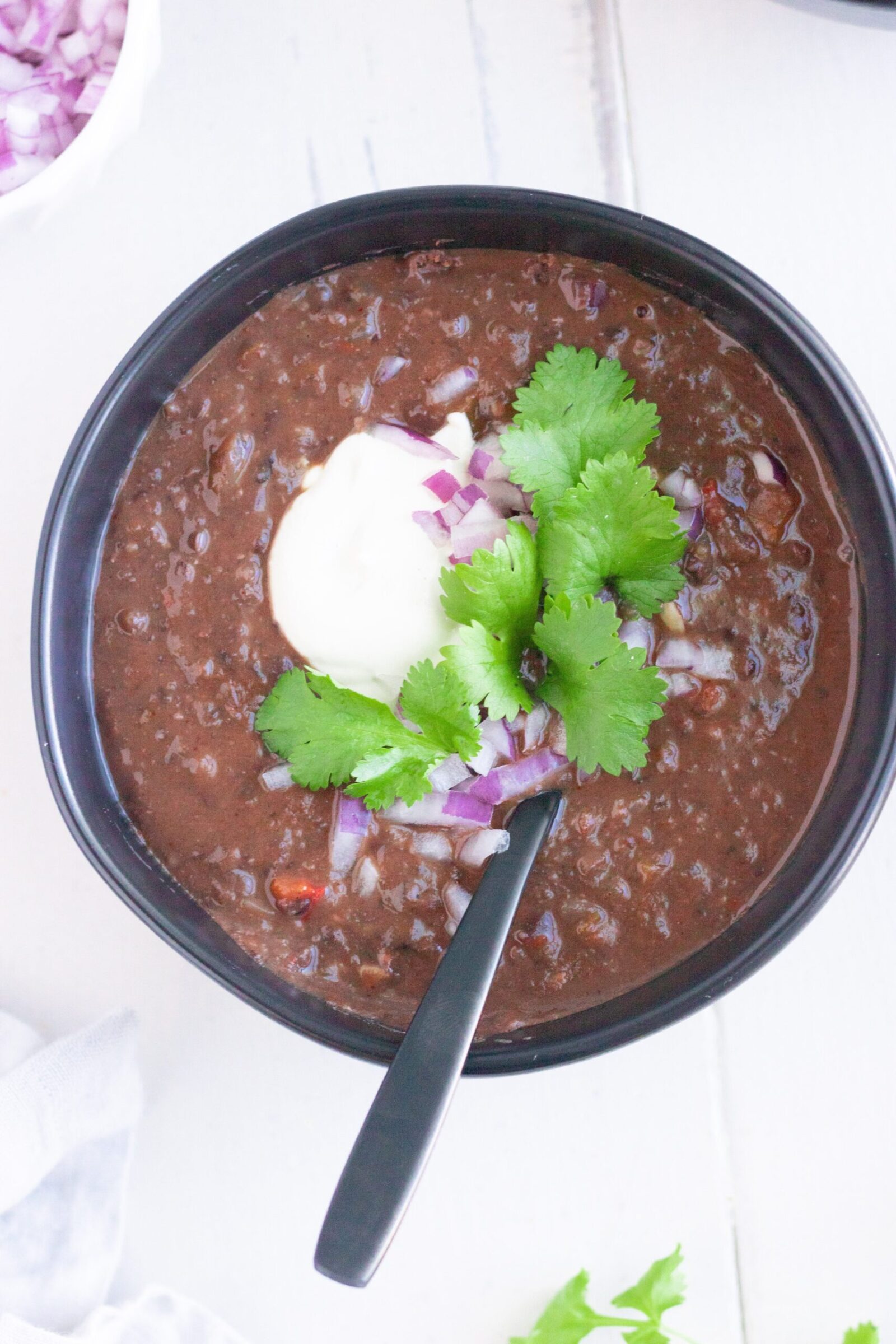 A bowl of Vegan Black Bean Soup with sour cream and cilantro.