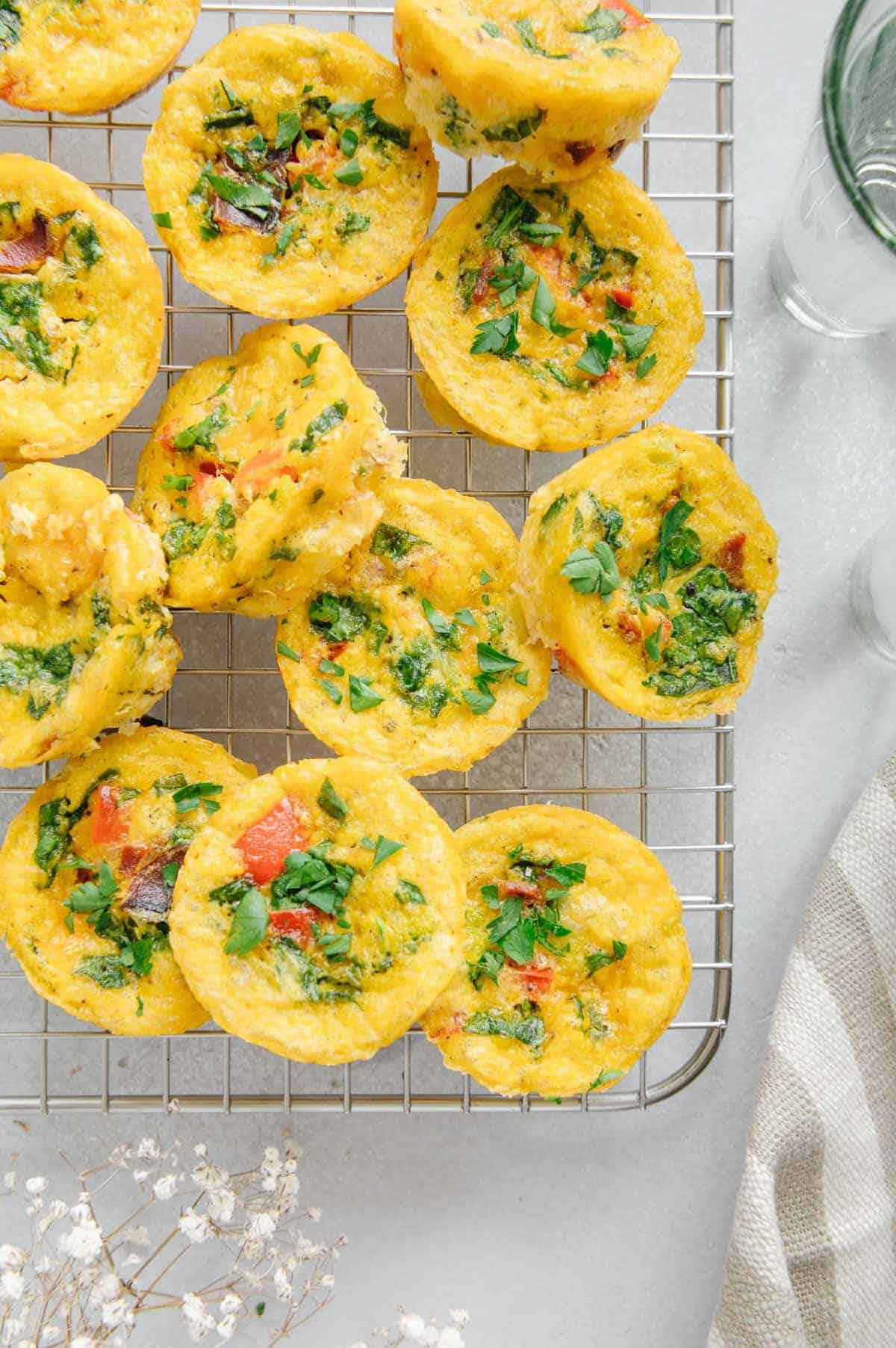 Several mini muffins with yellow eggy texture on a wire rack.