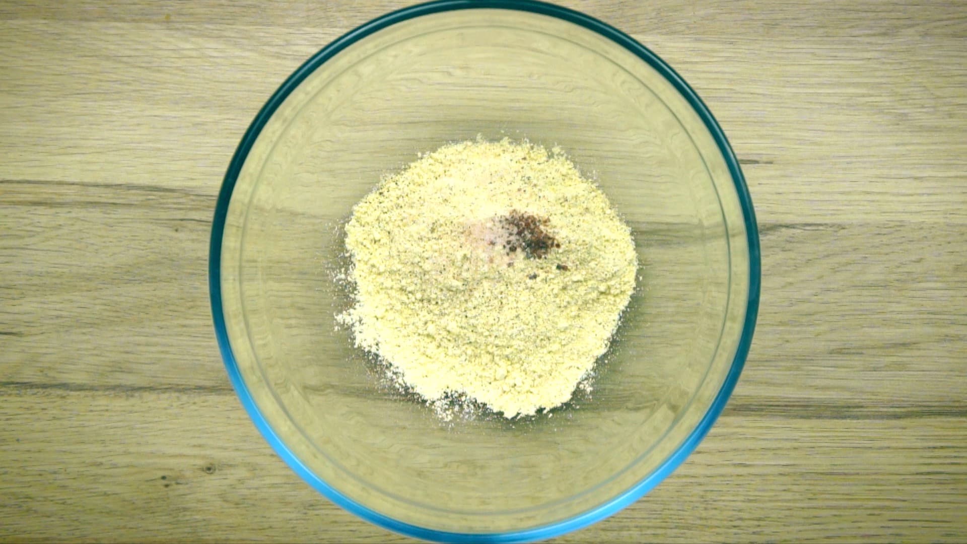 Glass bowl with yellow flour and small heaps of spices. 