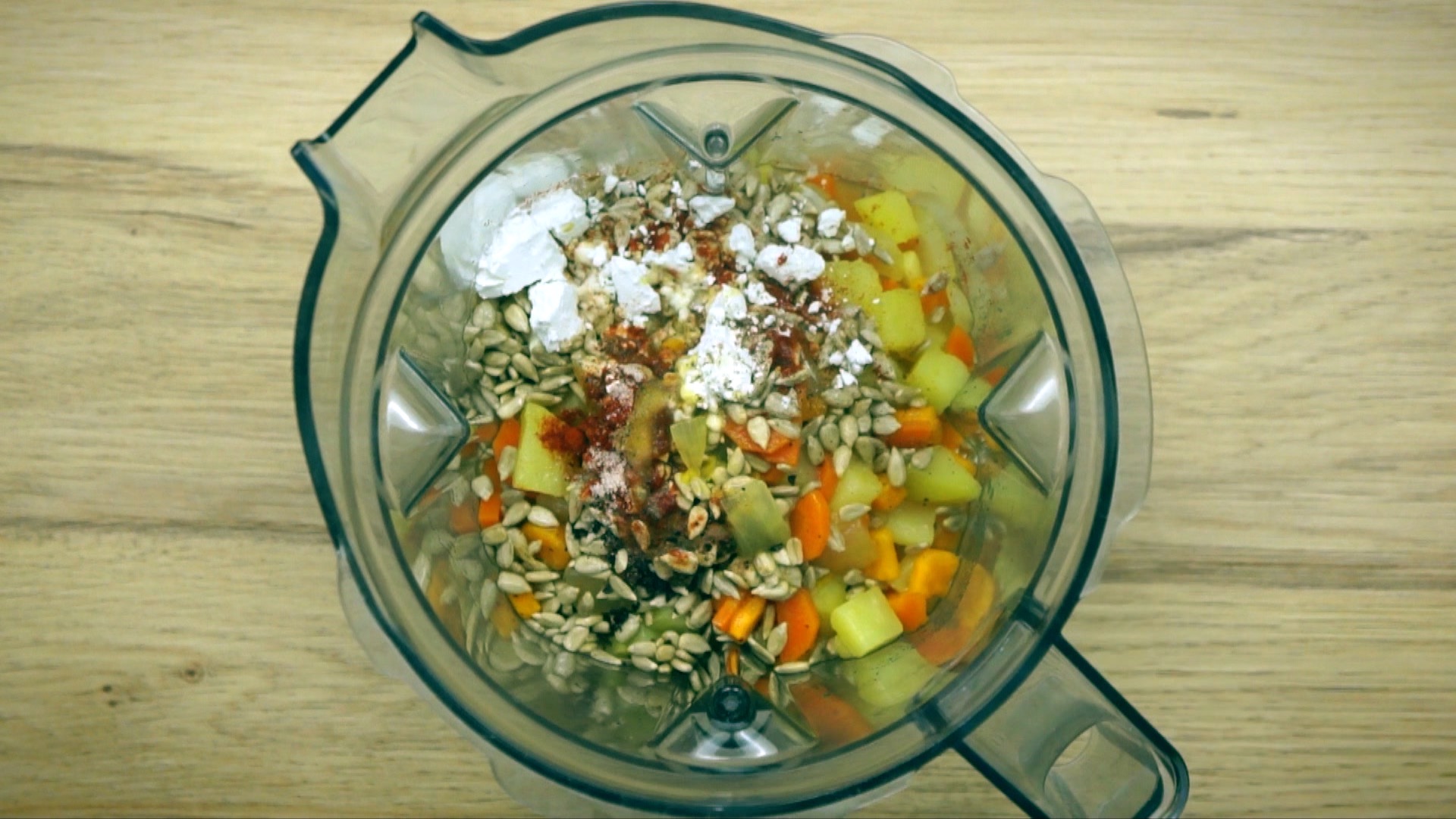 Blender with cooked diced carrots, potatoes, orange sweet potatoes, onions, garlic, sunflower seeds, paprika powder, and white corn starch.