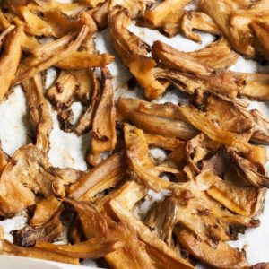 Shredded mushrooms scattered around a white parchment paper