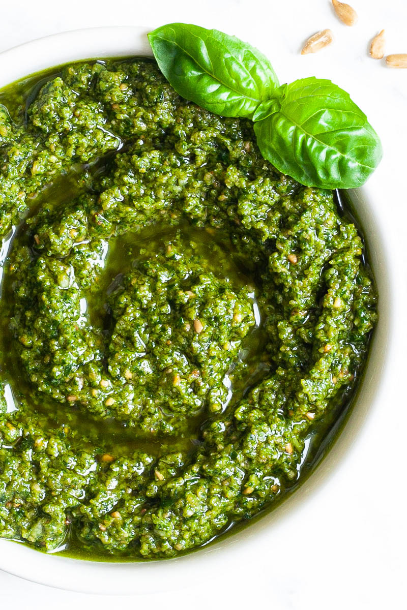 Small white bowl with a chunky green paste and a fresh basil leaf on the side.