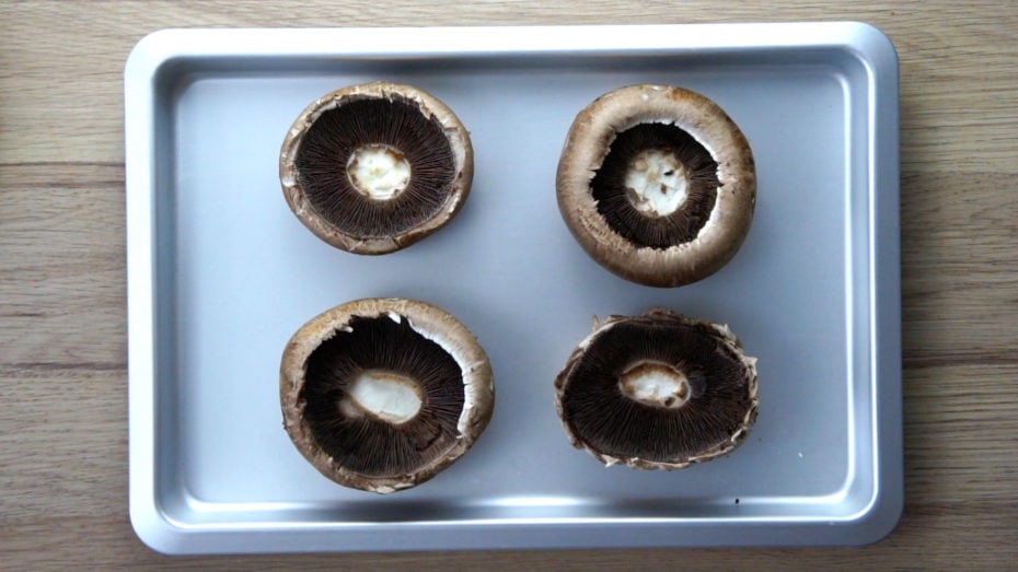 Silver baking tray with 4 mushroom caps turned upside down so the gills is visible. 