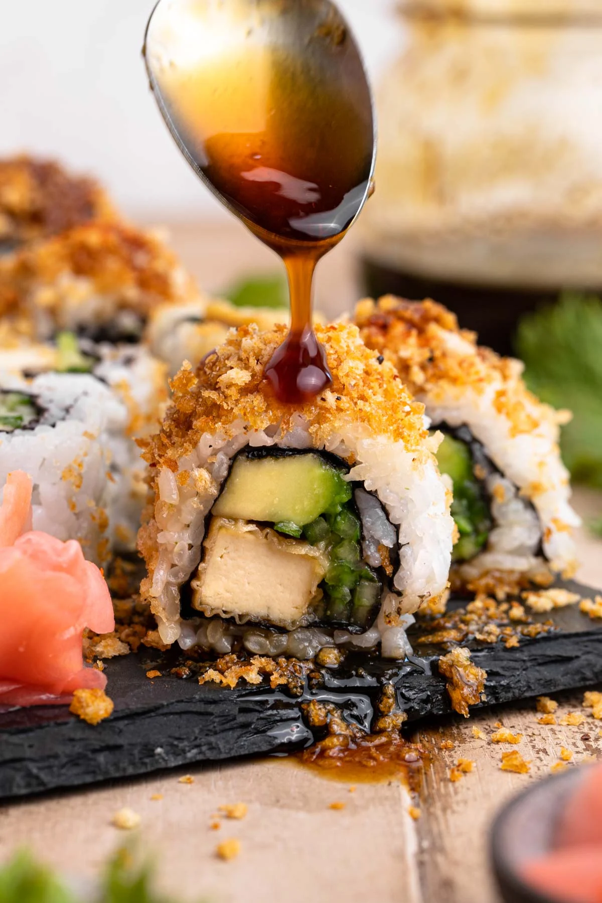 Tofu crunch sushi roll drizzled with a spoonful of teriyaki sauce. 